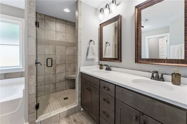 A well-appointed bathroom offers a glass-enclosed shower, dual vanity, and a window for natural light.