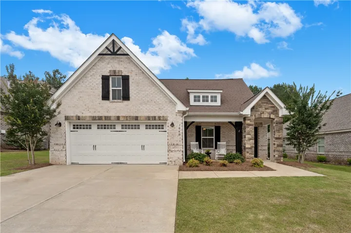 A charming single-story residence boasts a combination of brick and stone masonry, inviting covered porch, and attached garage.