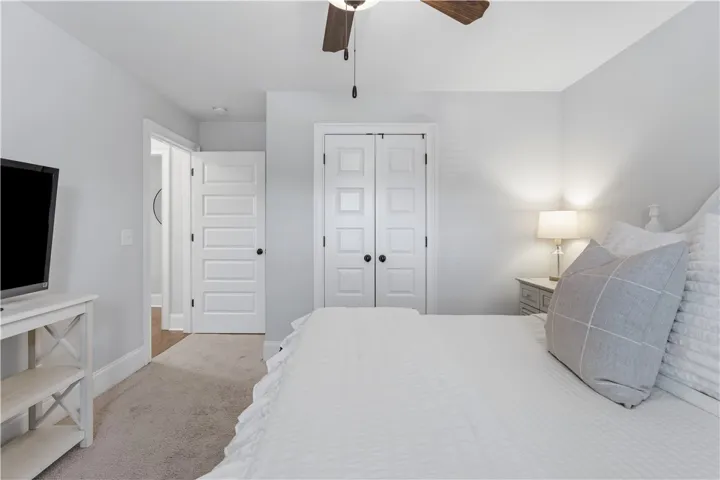 An inviting bedroom features a classic paneled door, ample closet space, and soft carpet underfoot.