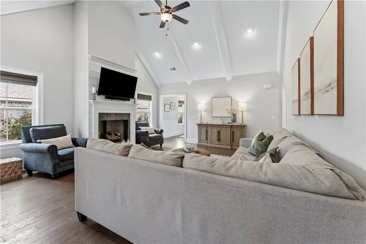 A welcoming living room featuring vaulted ceilings, a cozy fireplace, and rich hardwood flooring.