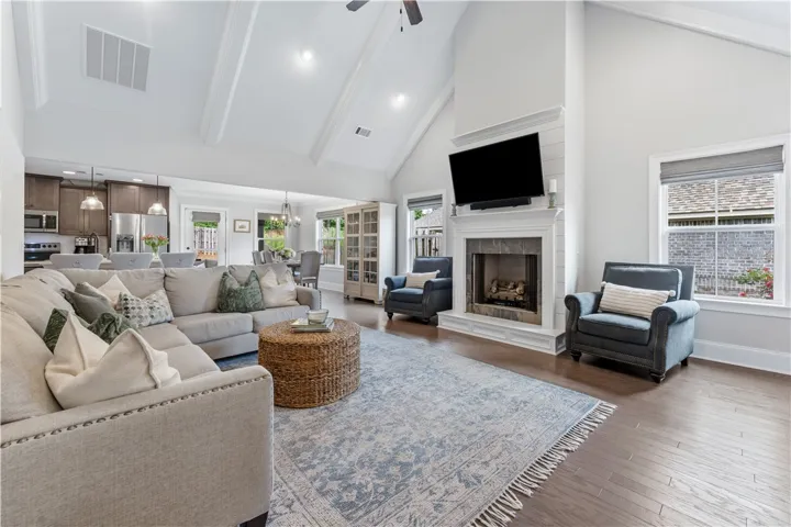 Soaring vaulted ceilings elevate a comfortable living space with a warm fireplace and rich hardwood flooring.