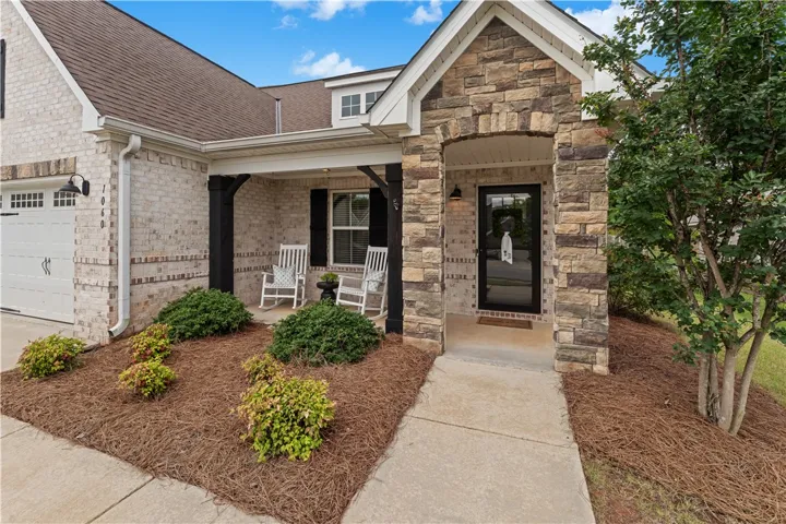 A welcoming front porch with stone and brick accents offers a charming entrance to this residence.