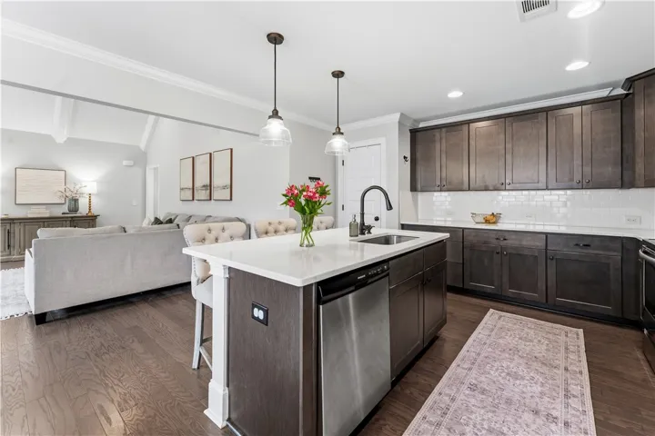 An open concept kitchen with a central island and sleek appliances flows into a comfortable living area.