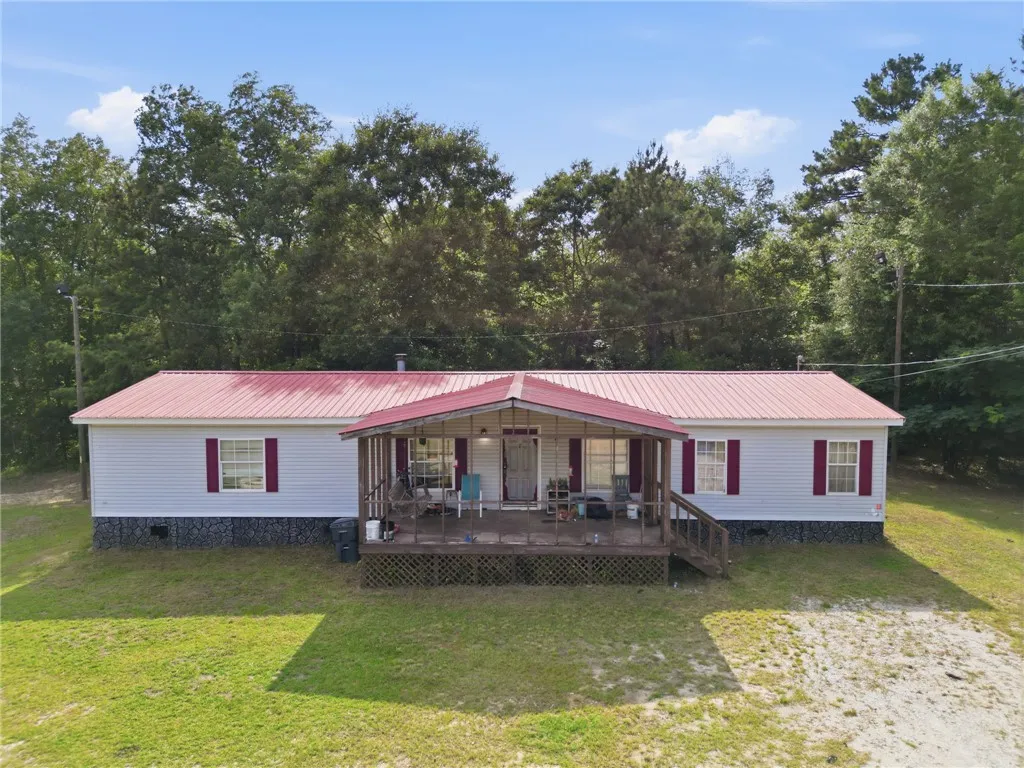 A charming single-story residence with a welcoming front porch and vibrant red metal roof.