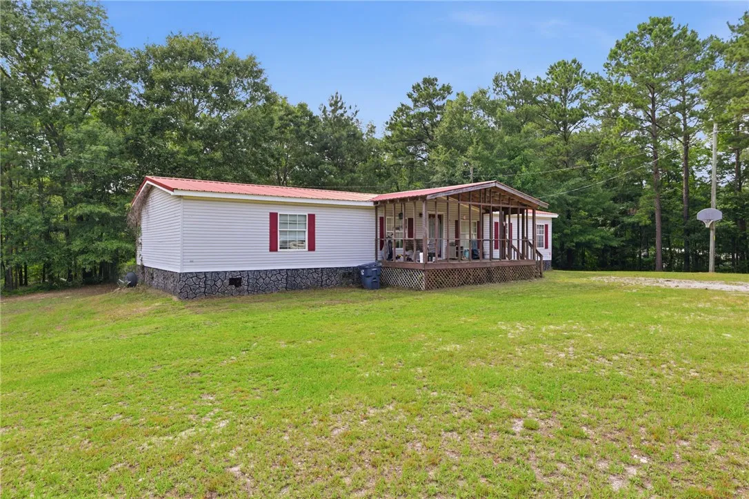 A welcoming front porch extends across this charming single-level home, nestled among mature trees.