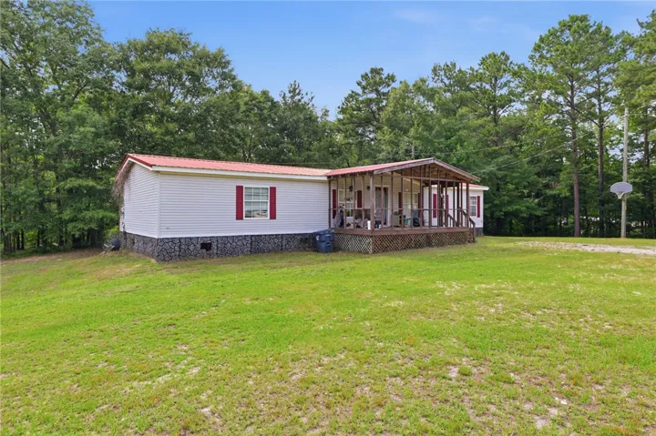 A welcoming front porch extends across this charming single-level home, nestled among mature trees.
