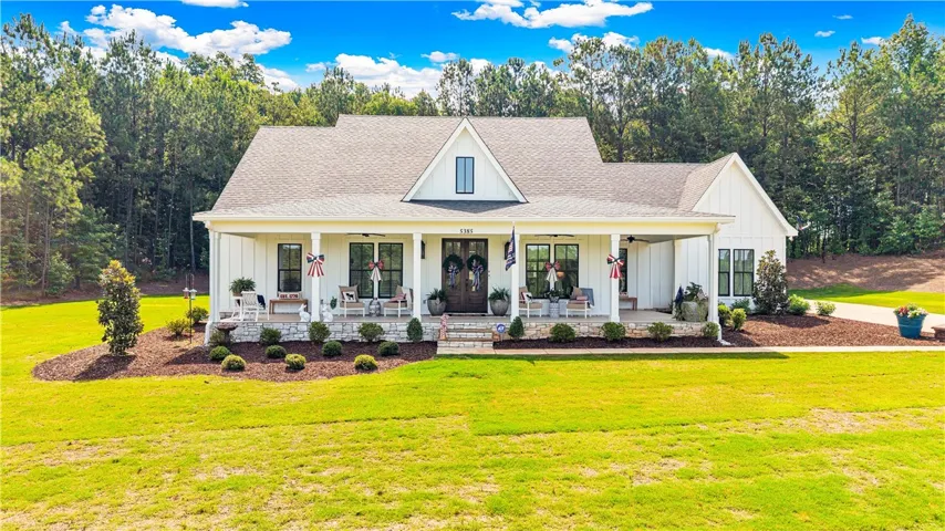 A classic white farmhouse, complete with a welcoming front porch, offers serene country living.