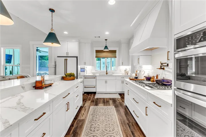 White cabinetry, elegant countertops, and modern appliances outfit this meticulously designed culinary space.