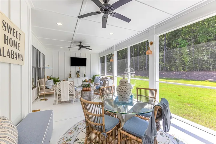 A spacious screened porch with coffered ceilings and multiple ceiling fans offers serene views of the surrounding natural landscape.
