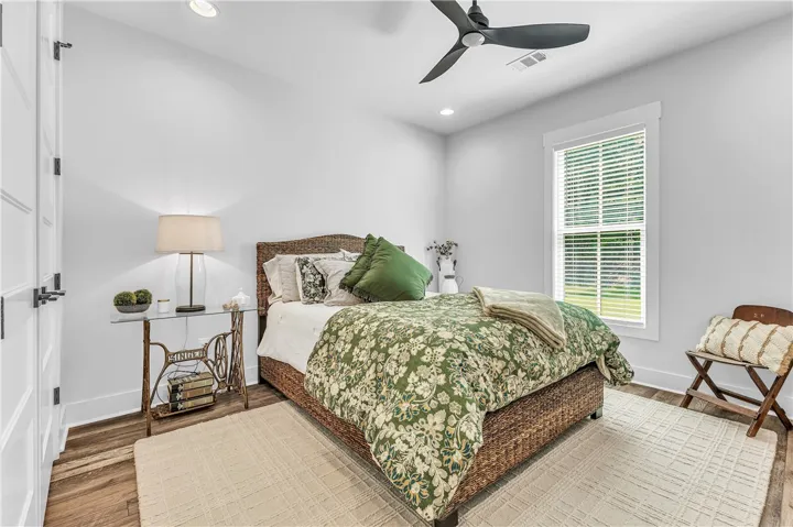 A well-lit bedroom with modern wood flooring and a refreshing ceiling fan.