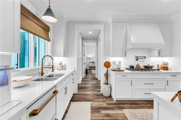 Culinary aspirations come alive in this well-appointed kitchen, boasting rich wood flooring and crisp white cabinetry.