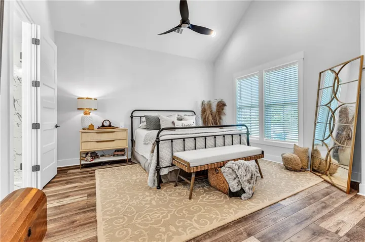 Lofty vaulted ceilings elevate this well-appointed bedroom, showcasing rich hardwood flooring.