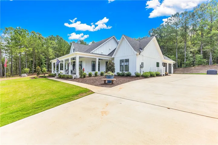 White siding and dark-framed windows distinguish this inviting residence, surrounded by mature trees.