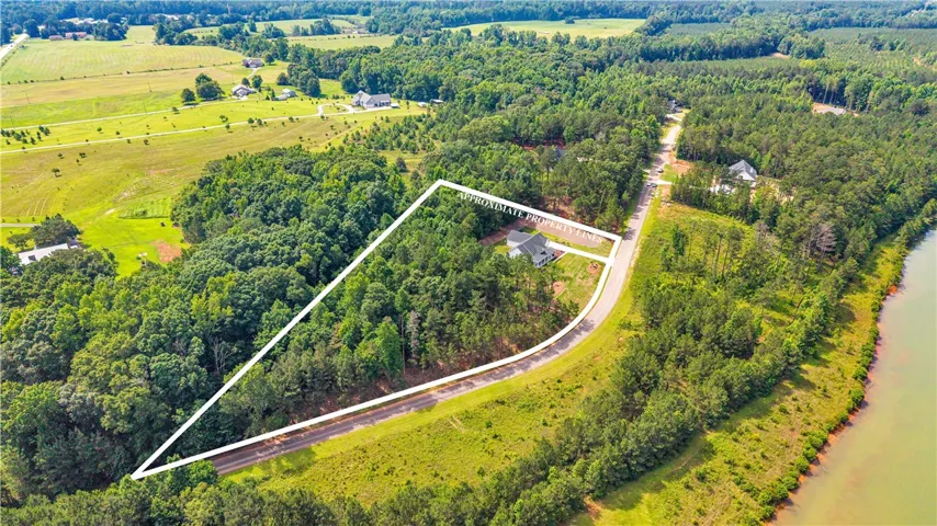 A private, tree-lined estate with ample outdoor space borders a serene body of water.