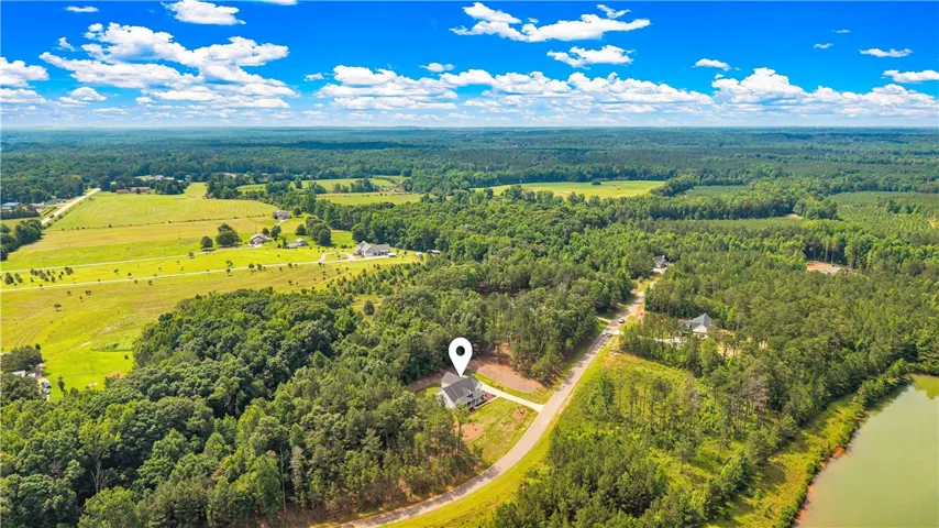 Vast green acreage surrounds this tranquil lakeside residence, offering privacy and scenic rural living.
