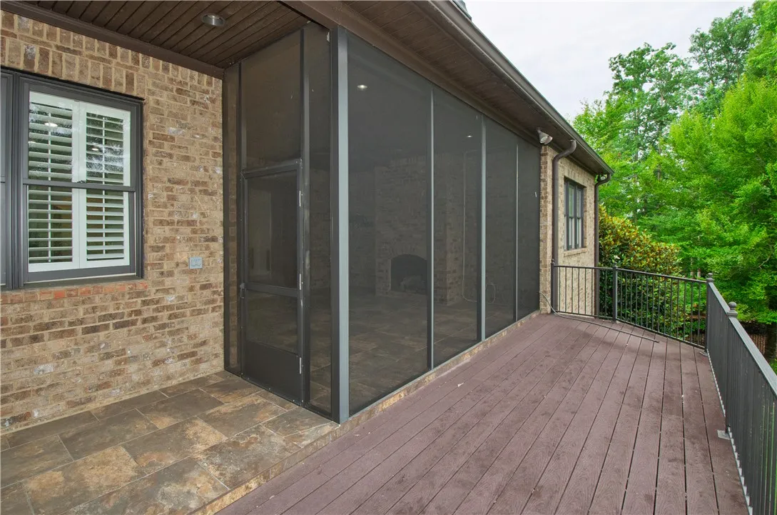 A spacious screened-in porch and open deck extend invitingly from a classic brick facade, offering tranquil outdoor living.