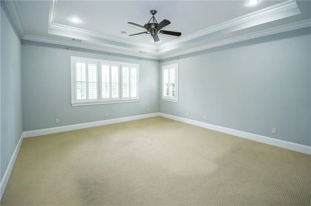 Recessed lighting and a classic ceiling fan crown this inviting bedroom, offering both illumination and air circulation.