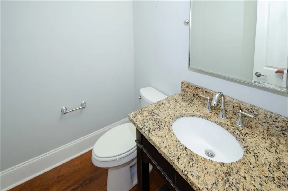 A well-appointed powder room features granite counters and hardwood floors.