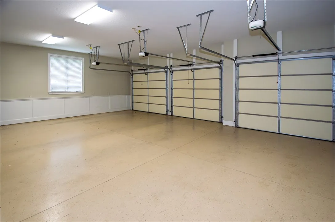 A spacious, well-lit garage with three bays and durable concrete flooring.