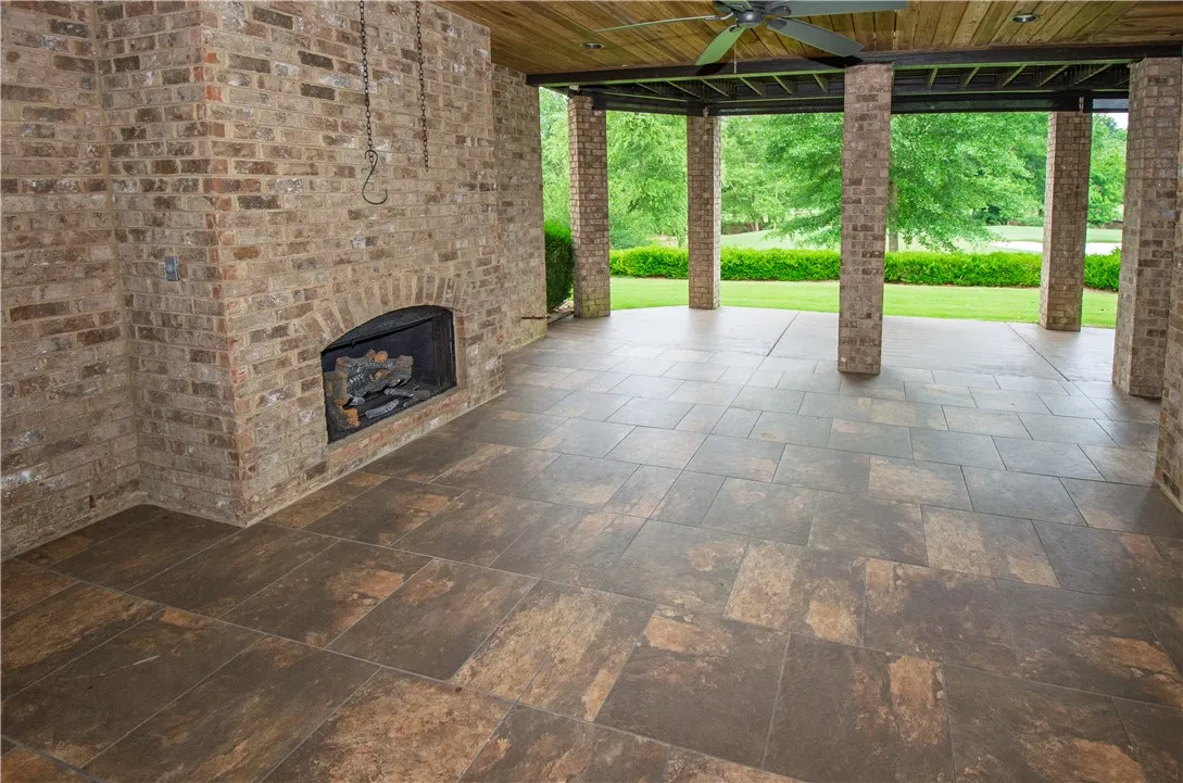 An inviting covered patio featuring a brick fireplace and a rich, tiled floor, perfect for outdoor enjoyment.