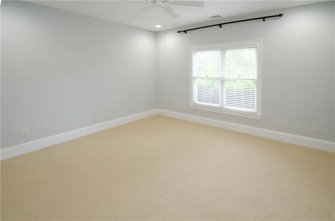 A well-lit, neutral-toned room features a wide window, offering ample natural illumination.
