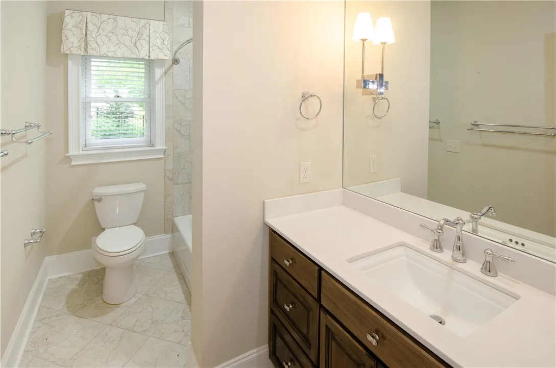 A well-appointed bathroom features a single vanity, ample mirror, and a window for natural light.