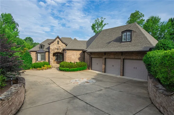 Elegant brick and stone facade welcomes guests with a spacious driveway and attached garages.