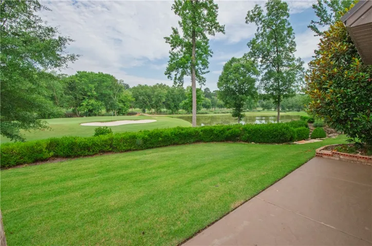 An immaculate lawn transitions to a golf course, bordered by a tranquil pond and lush greenery.