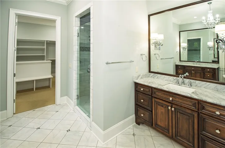 Marble-topped vanity and custom cabinetry define this elegant primary bathroom.