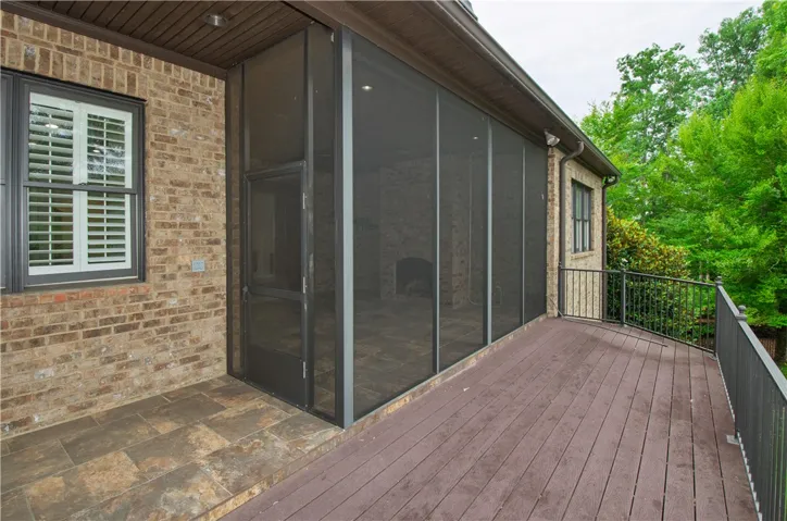 A spacious screened-in porch and open deck extend invitingly from a classic brick facade, offering tranquil outdoor living.