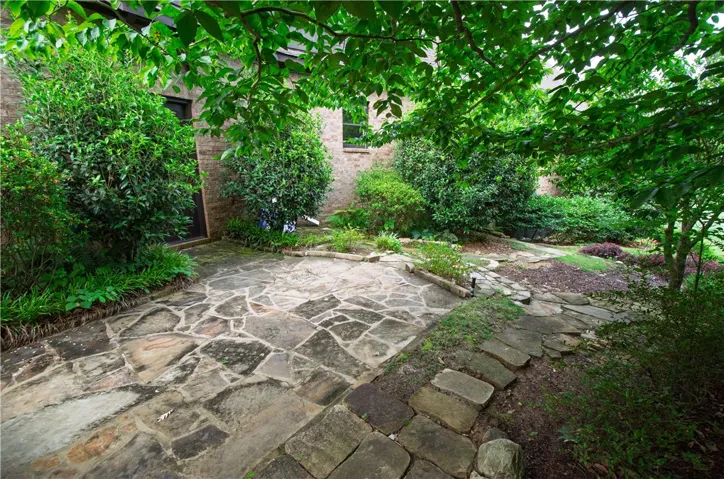 A tranquil flagstone patio area provides a private outdoor retreat, surrounded by verdant plantings.