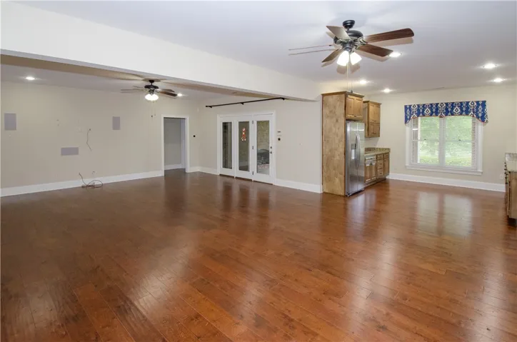 Rich hardwood flooring extends throughout this versatile living area, complemented by sleek ceiling fans.