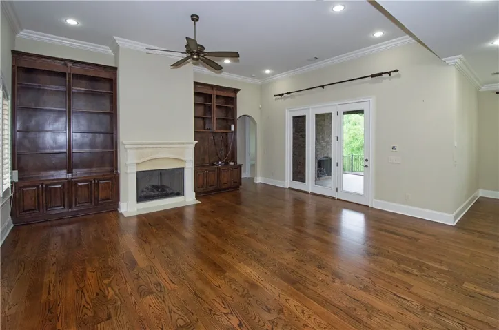 Rich hardwood flooring complements the detailed built-in shelving and fireplace in this inviting living space.