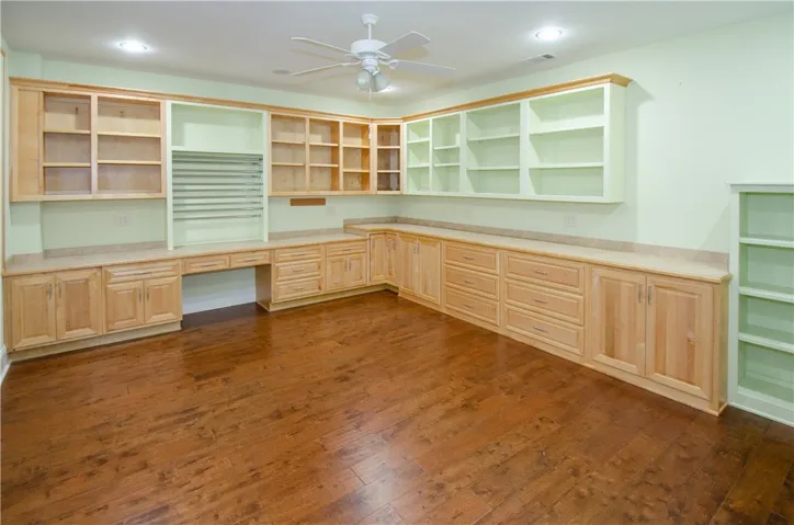 Custom built-in cabinetry and warm hardwood flooring define this versatile home office or craft space.