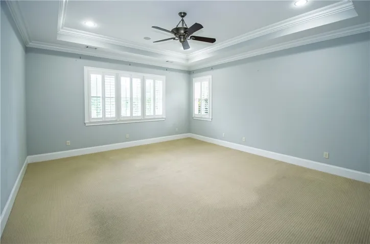 Recessed lighting and a classic ceiling fan crown this inviting bedroom, offering both illumination and air circulation.