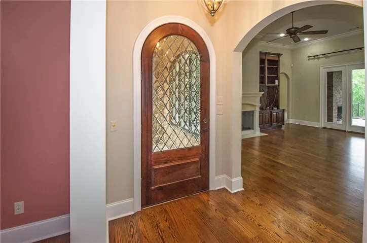 An inviting leaded-glass entry door opens to gleaming hardwood floors and an arched doorway leading to the living space.