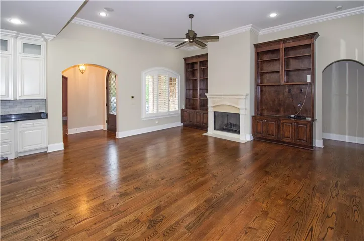 Rich hardwood floors complement built-in shelving surrounding a stately fireplace, defining this spacious living area.