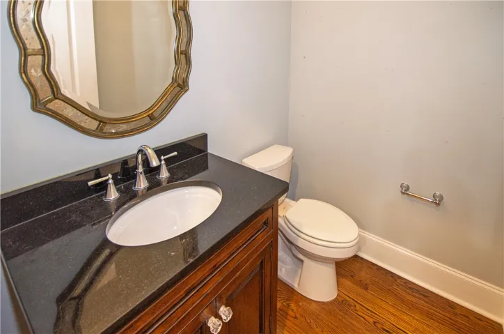 A well-appointed powder room with a dark granite vanity and a decorative mirror.