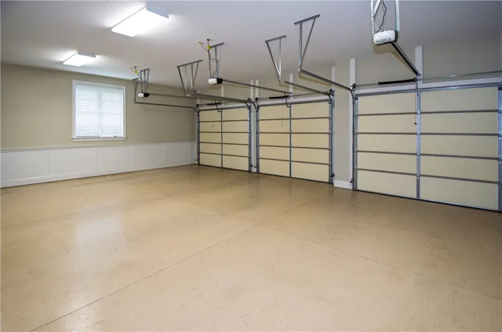 A spacious, well-lit garage with three bays and durable concrete flooring.