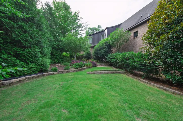 A tiered landscape with lush greenery, retaining walls, and a manicured lawn.