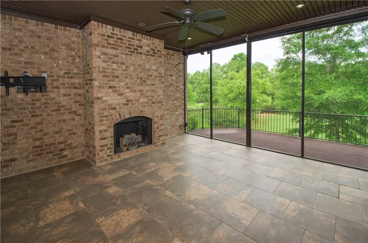 An inviting screened-in porch features a brick fireplace and tranquil tree-lined views.