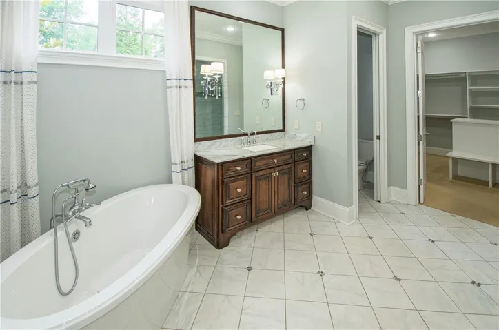 Indulge in a tranquil bathing experience with this deep soaking tub and elegant marble-topped vanity.