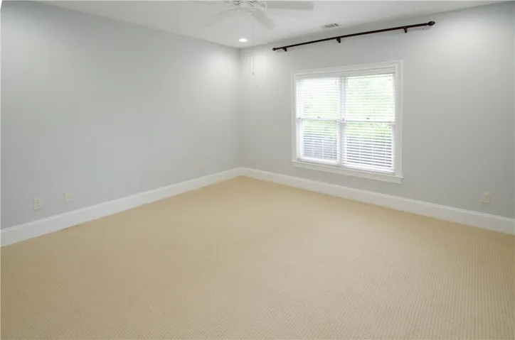 A well-lit, neutral-toned room features a wide window, offering ample natural illumination.