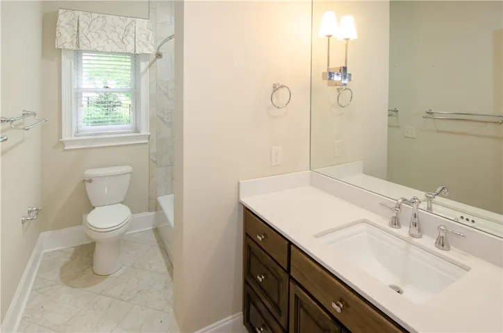 A well-appointed bathroom features a single vanity, ample mirror, and a window for natural light.