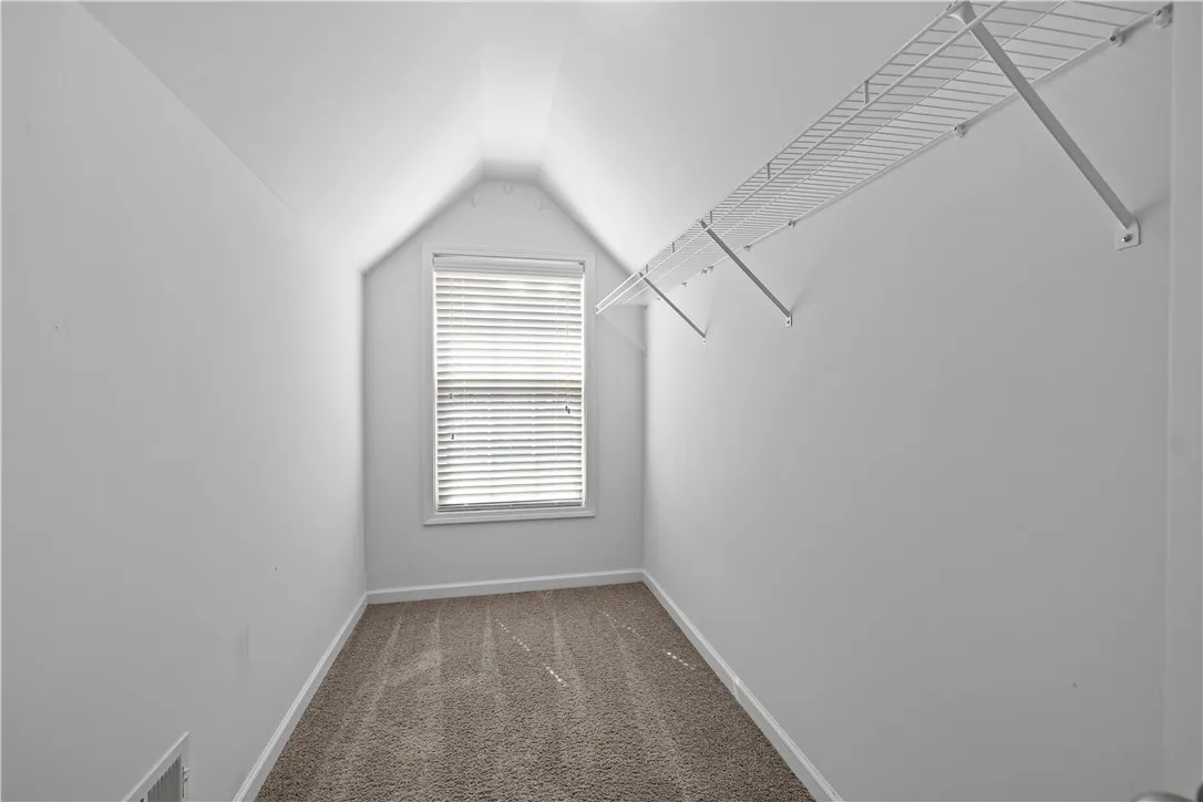 Ample storage solutions are provided by the efficient wire shelving system within this bright, compact walk-in closet.