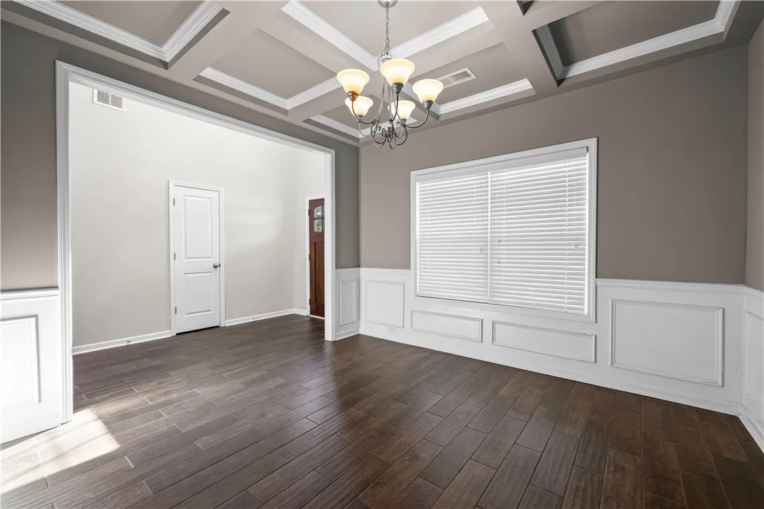 Elegant coffered ceilings crown this spacious dining area with rich hardwood flooring and classic wainscoting.