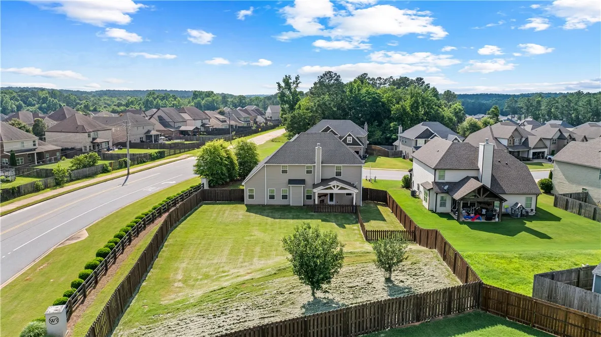 An aerial perspective reveals a spacious backyard and covered patio in a vibrant neighborhood setting.