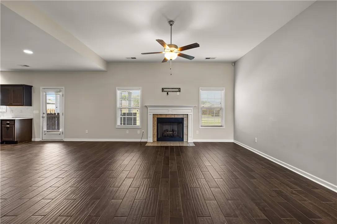 A spacious living area with warm wood flooring centers around a cozy fireplace, perfect for gatherings.