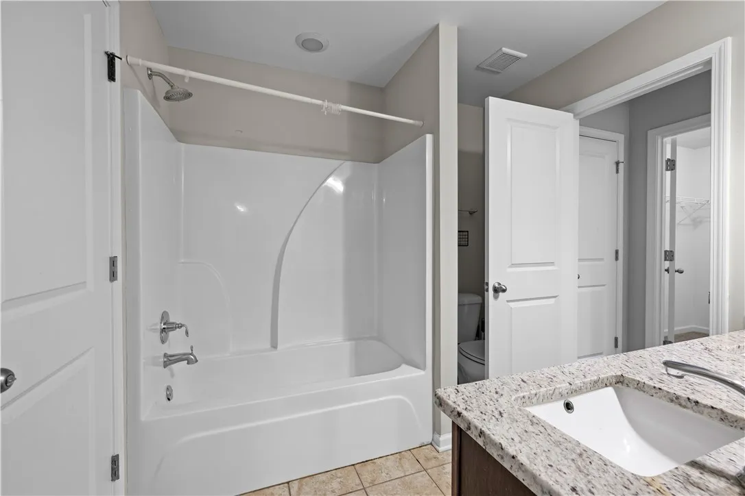 A well-appointed bathroom with a white tub-shower combination and a vanity featuring granite counters.
