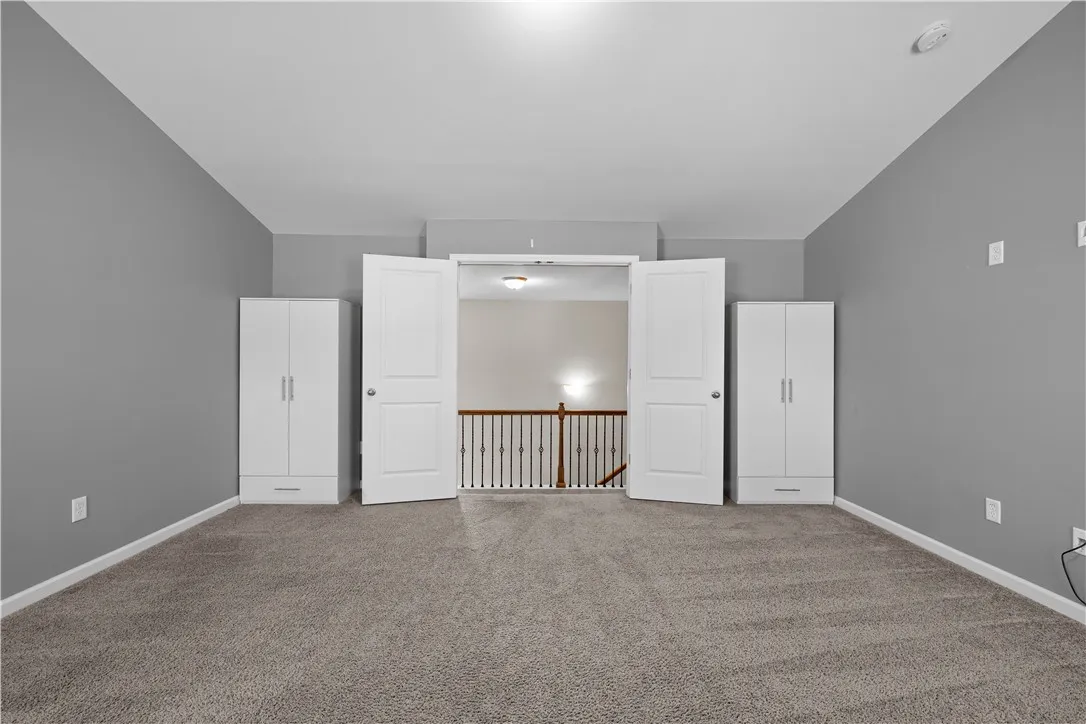 A well-lit upper level space with carpeted flooring opens to a view of the staircase below.
